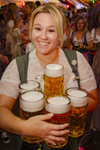 Frau serviert mehrere Biergläser beim RÜ Oktoberfest // Flughafen Essen/Mülheim